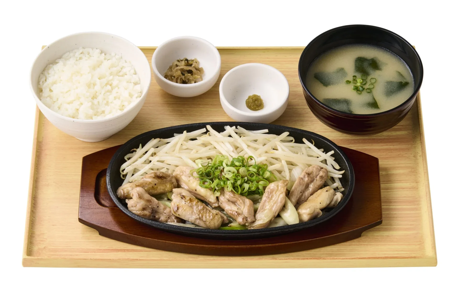 木製トレイに盛り付けられた和食の定食です。メインは鶏肉ともやしの鉄板焼きで、ご飯、わかめとネギの味噌汁、漬物、薬味が添えられています。全体的にバランスの取れたヘルシーな食事が表現されています。