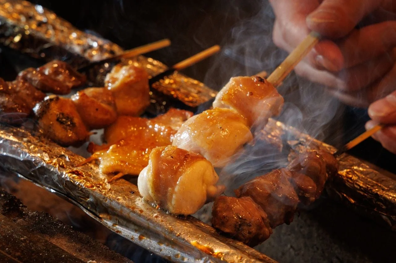 炭火で焼かれる串に刺さった鶏肉