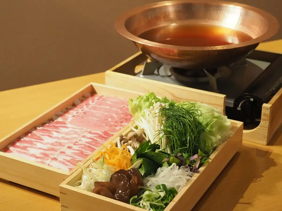 銅製の鍋と肉・野菜の食卓風景